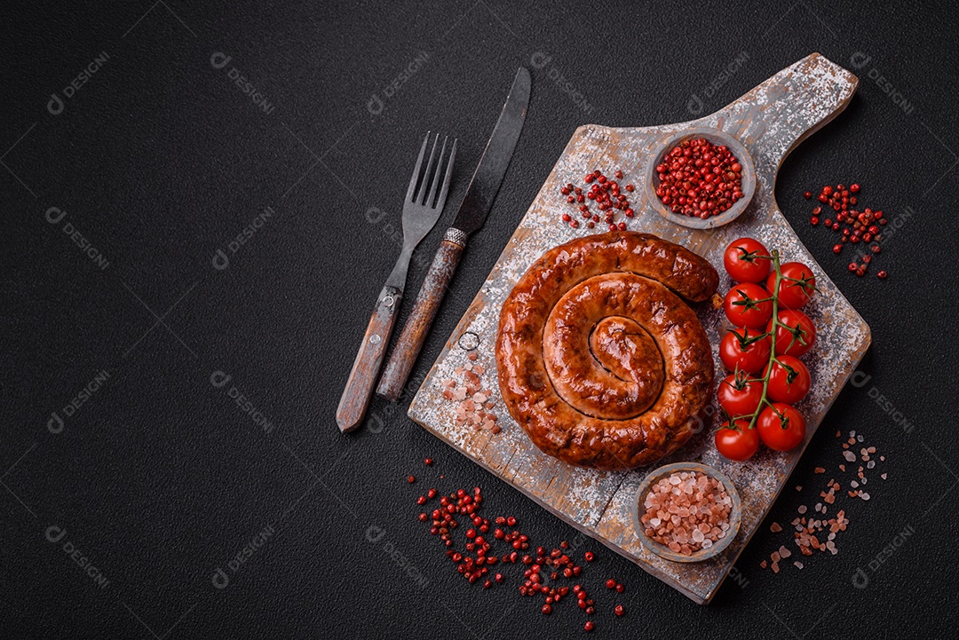 Deliciosa salsicha caseira em forma de espiral assada na grelha com sal, especiarias e ervas sobre um fundo escuro de concreto