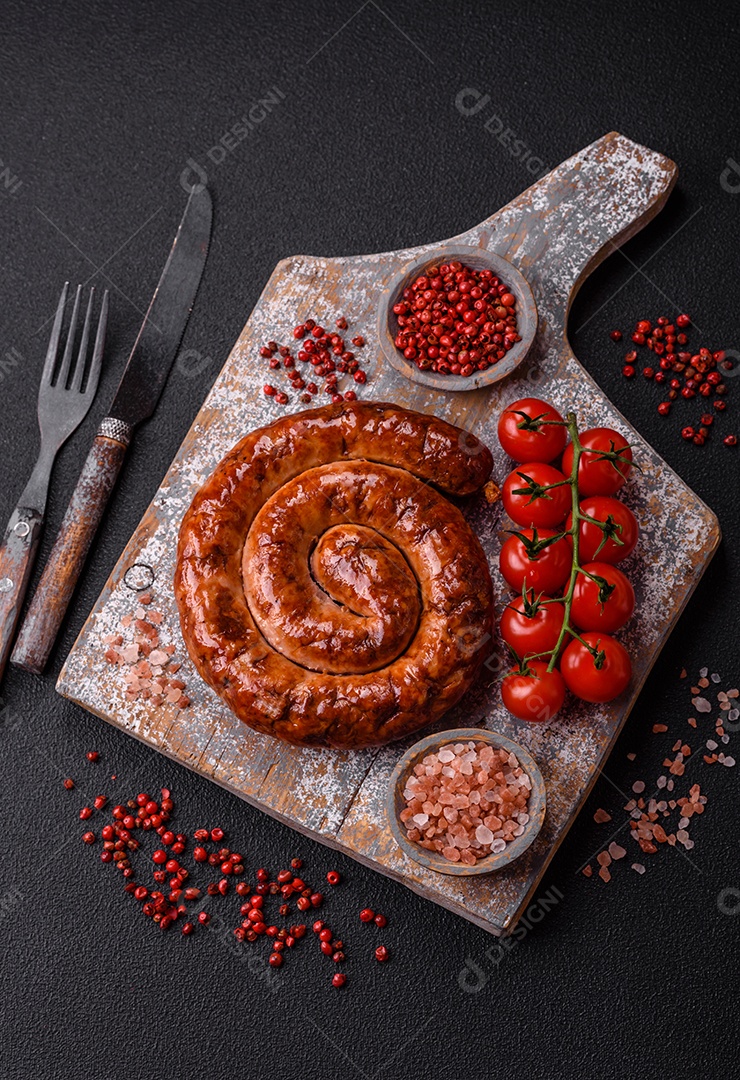 Deliciosa salsicha caseira em forma de espiral assada na grelha com sal, especiarias e ervas sobre um fundo escuro de concret
