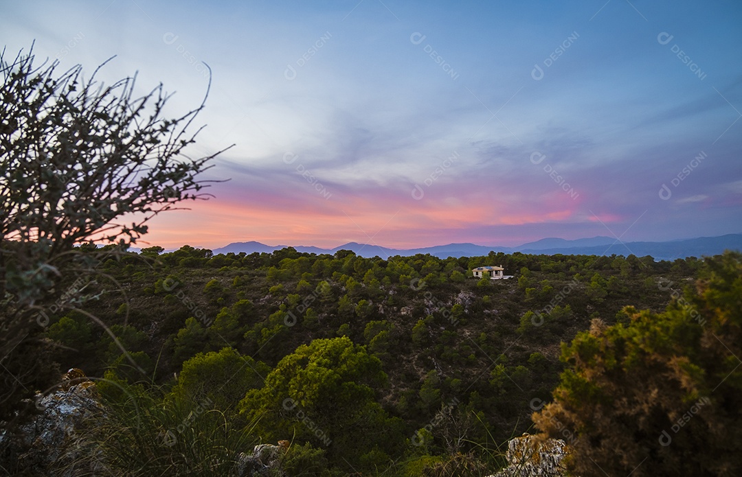Vista de uma pequena casa isolada no topo da montanha ao entardecer