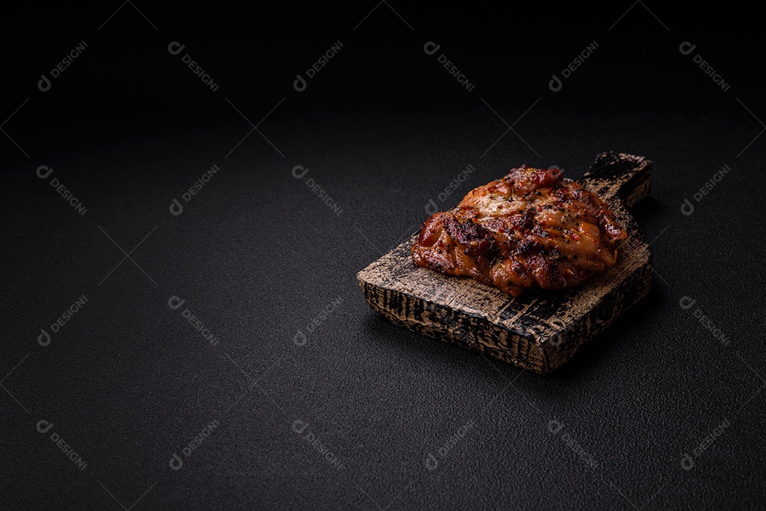 Delicioso bife de frango suculento com sal, especiarias e ervas sobre um fundo escuro de concreto