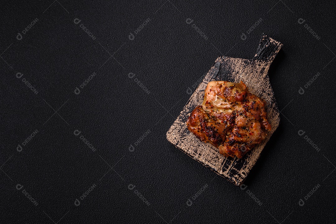 Delicioso bife de frango suculento com sal, especiarias e ervas sobre um fundo escuro de concreto