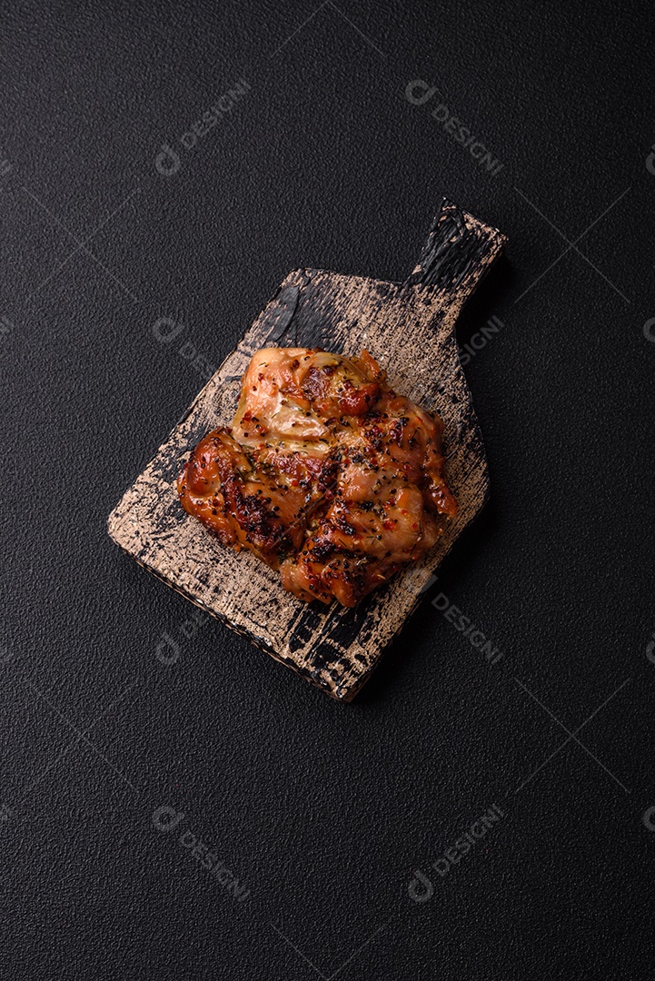 Delicioso bife de frango suculento com sal, especiarias e ervas sobre um fundo escuro de concreto