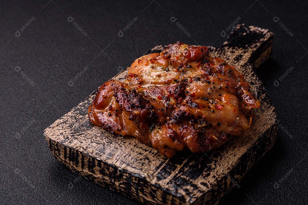 Delicioso bife de frango suculento com sal, especiarias e ervas sobre um fundo escuro de concreto