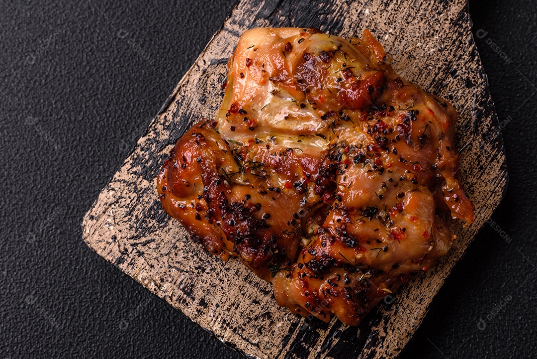 Delicioso bife de frango suculento com sal, especiarias e ervas sobre um fundo escuro de concreto