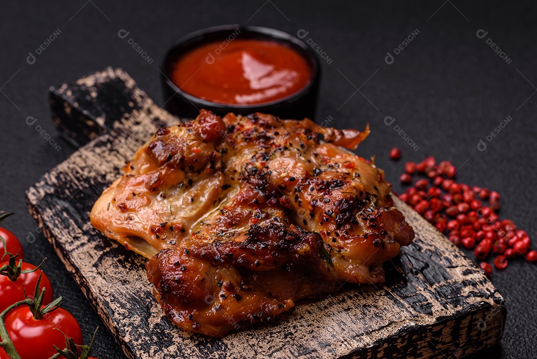 Delicioso bife de frango suculento com sal, especiarias e ervas sobre um fundo escuro de concreto