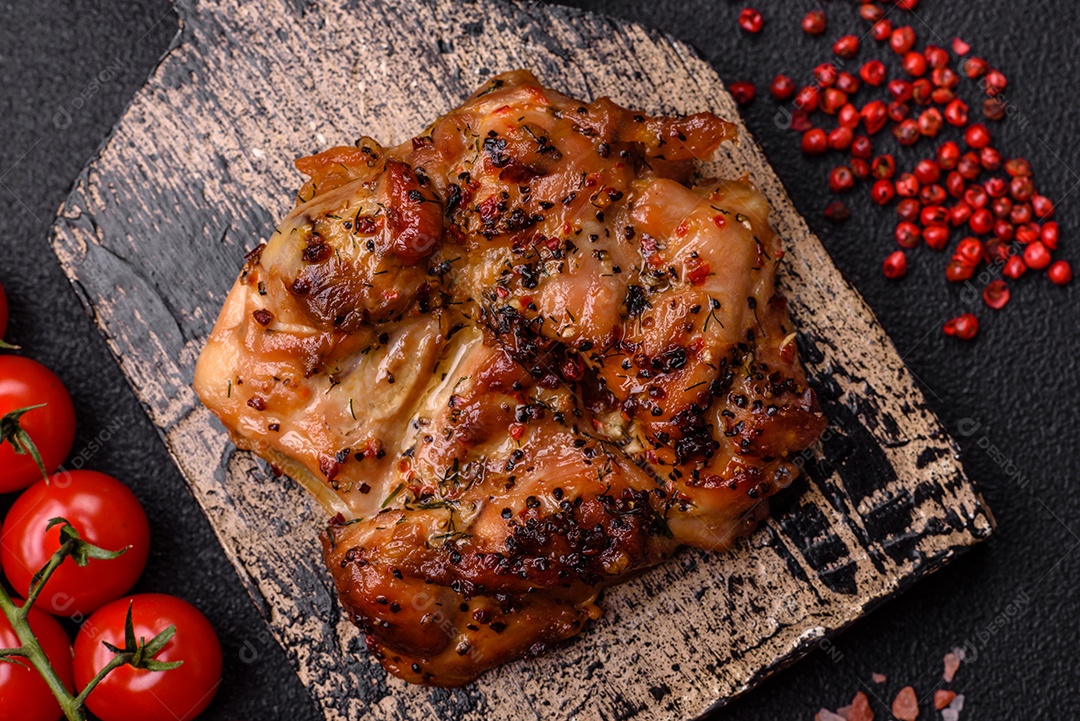 Delicioso bife de frango suculento com sal, especiarias e ervas sobre um fundo escuro de concreto