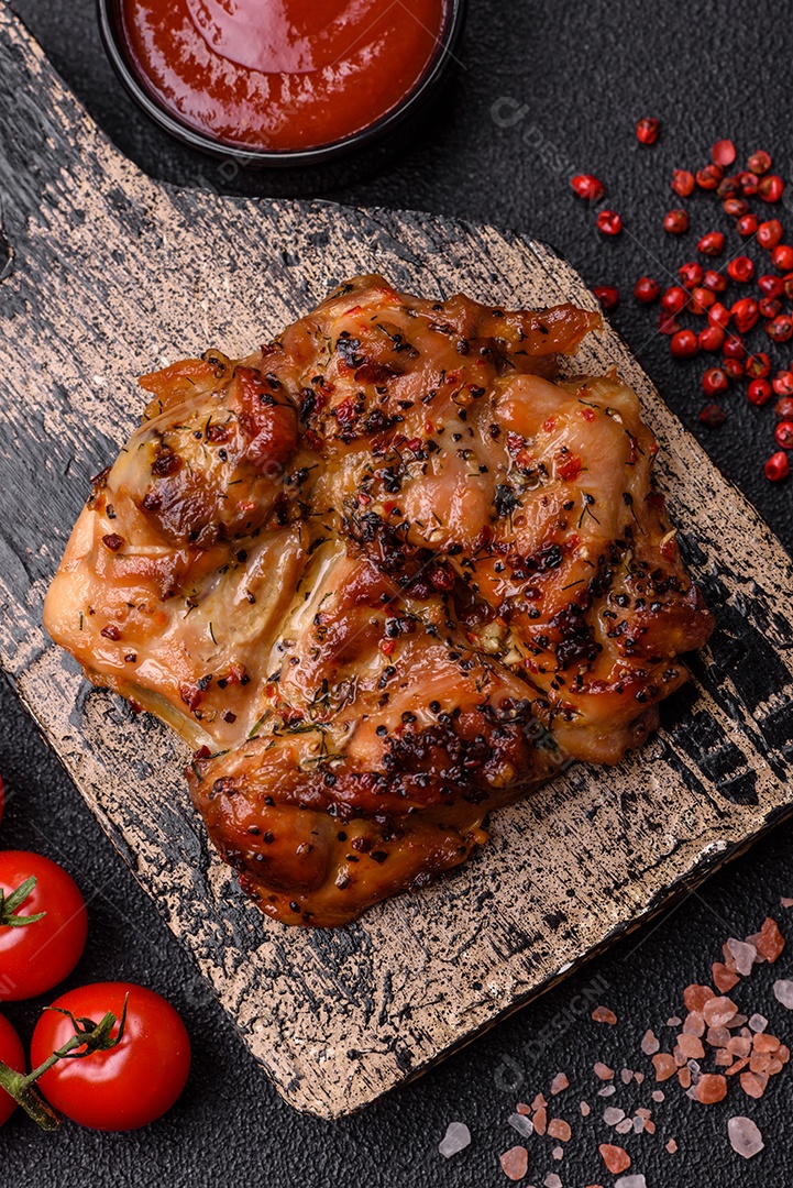 Delicioso bife de frango suculento com sal, especiarias e ervas sobre um fundo escuro de concreto