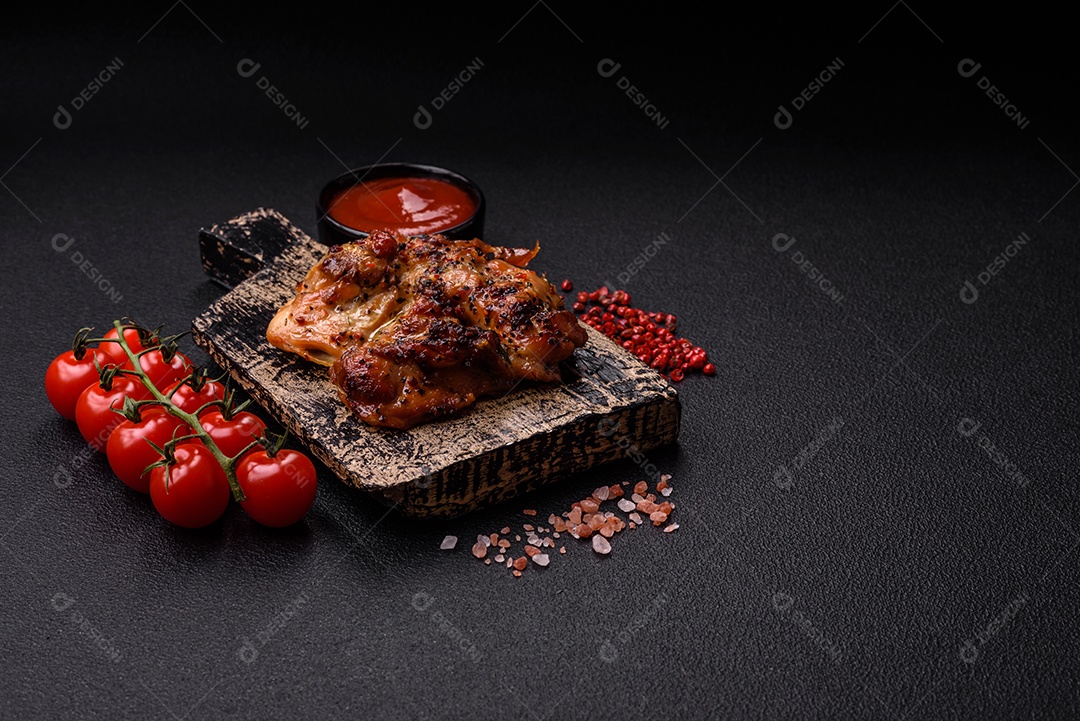 Delicioso bife de frango suculento com sal, especiarias e ervas sobre um fundo escuro de concreto