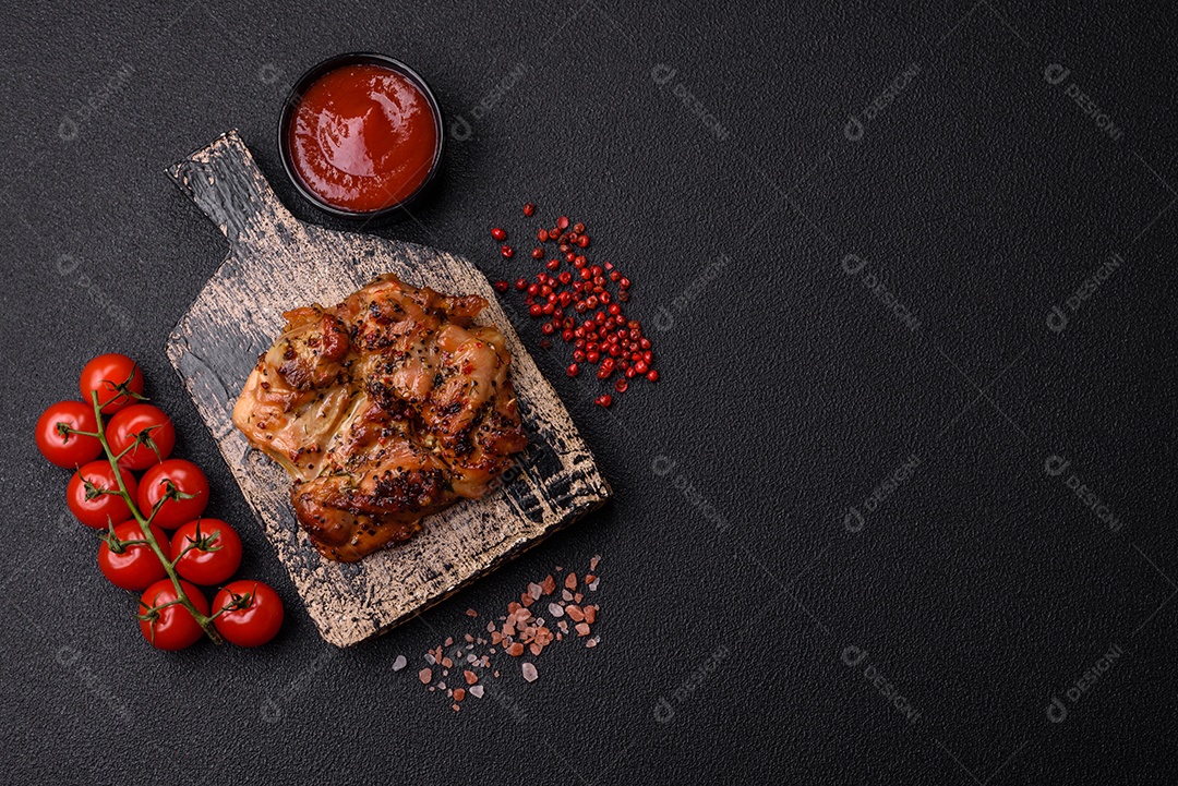 Delicioso bife de frango suculento com sal, especiarias e ervas sobre um fundo escuro de concreto