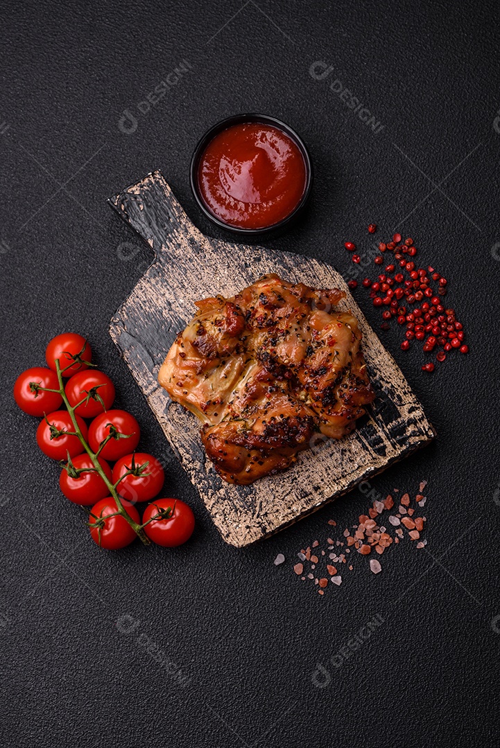 Delicioso bife de frango suculento com sal, especiarias e ervas sobre um fundo escuro de concreto