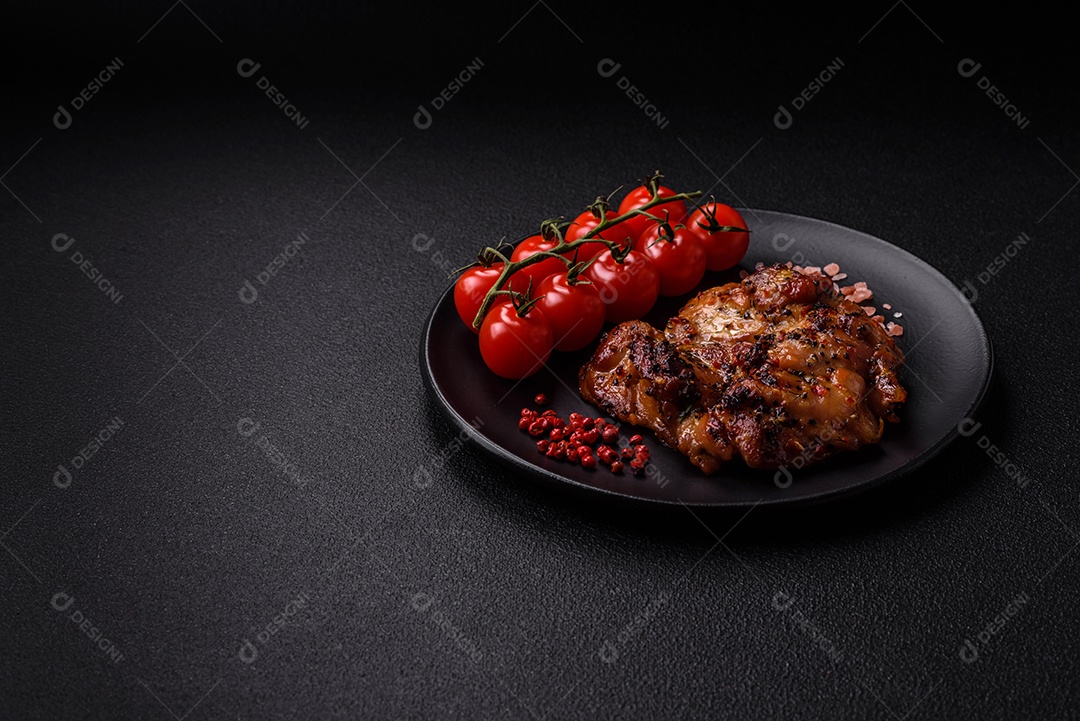 Delicioso bife de frango suculento com sal, especiarias e ervas sobre um fundo escuro de concreto