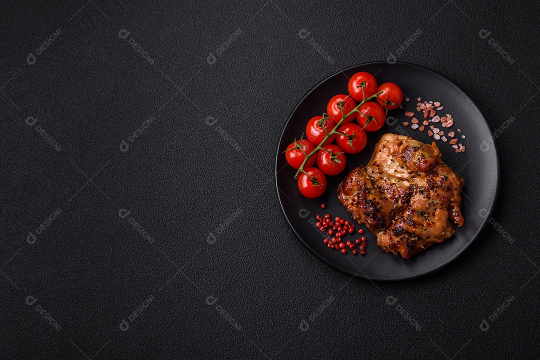 Delicioso bife de frango suculento com sal, especiarias e ervas sobre um fundo escuro de concreto