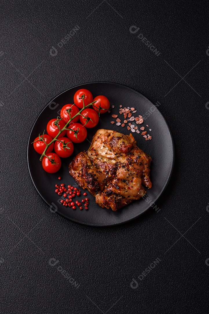 Delicioso bife de frango suculento com sal, especiarias e ervas sobre um fundo escuro de concreto