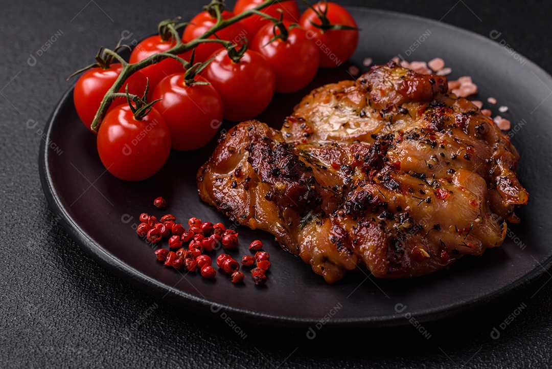 Delicioso bife de frango suculento com sal, especiarias e ervas sobre um fundo escuro de concreto