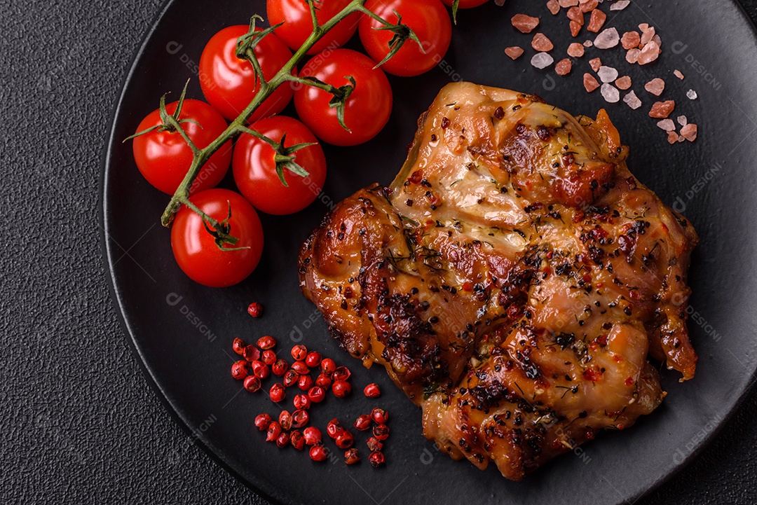 Delicioso bife de frango suculento com sal, especiarias e ervas sobre um fundo escuro de concreto