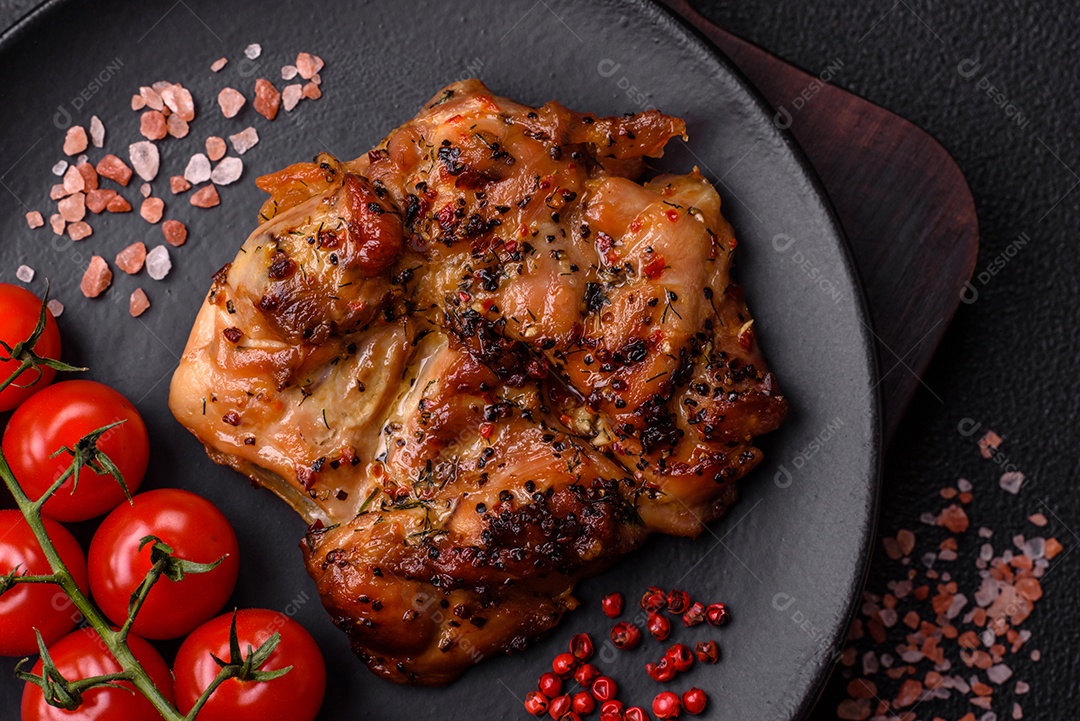 Delicioso bife de frango suculento com sal, especiarias e ervas sobre um fundo escuro de concreto