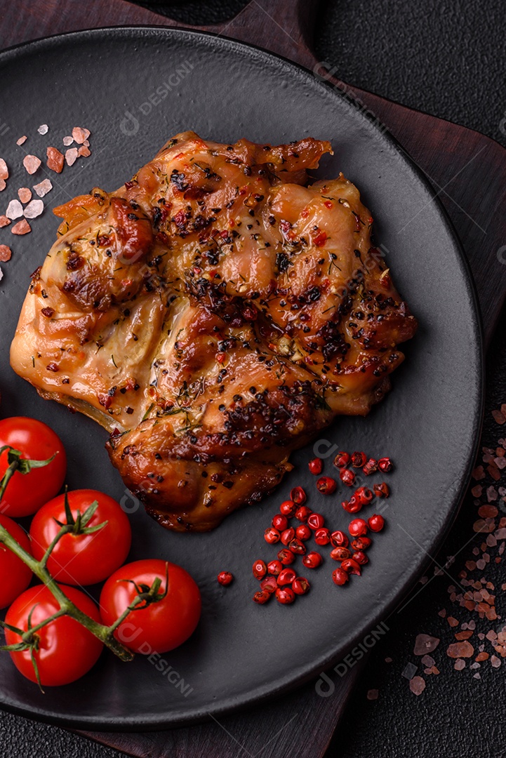 Delicioso bife de frango suculento com sal, especiarias e ervas sobre um fundo escuro de concreto