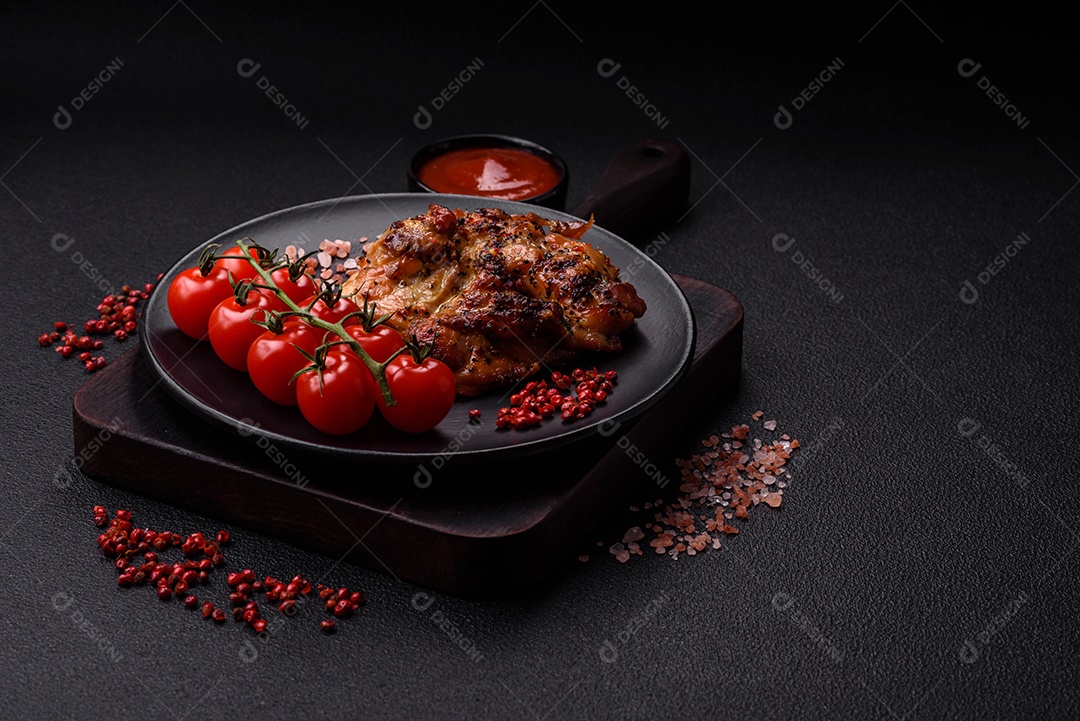 Delicioso bife de frango suculento com sal, especiarias e ervas sobre um fundo escuro de concreto