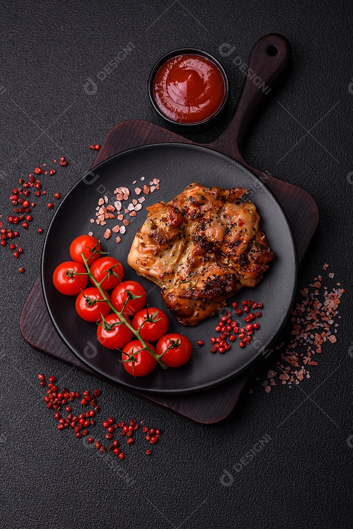 Delicioso bife de frango suculento com sal, especiarias e ervas sobre um fundo escuro de concreto