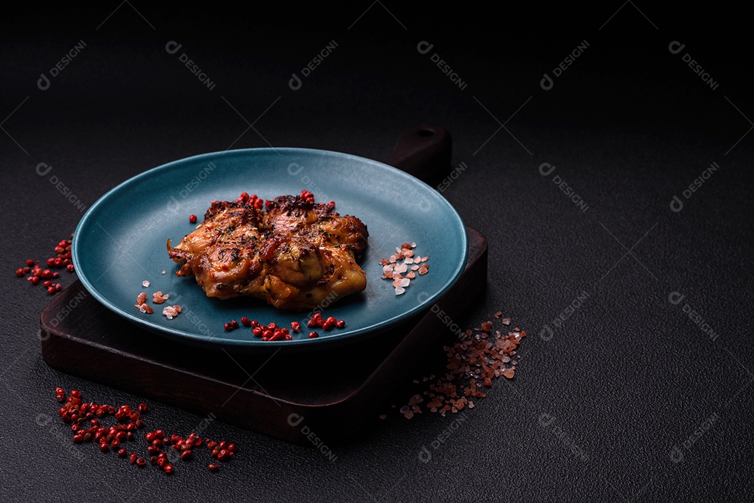 Delicioso bife de frango suculento com sal, especiarias e ervas sobre um fundo escuro de concreto