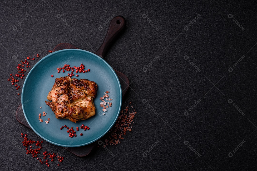 Delicioso bife de frango suculento com sal, especiarias e ervas sobre um fundo escuro de concreto