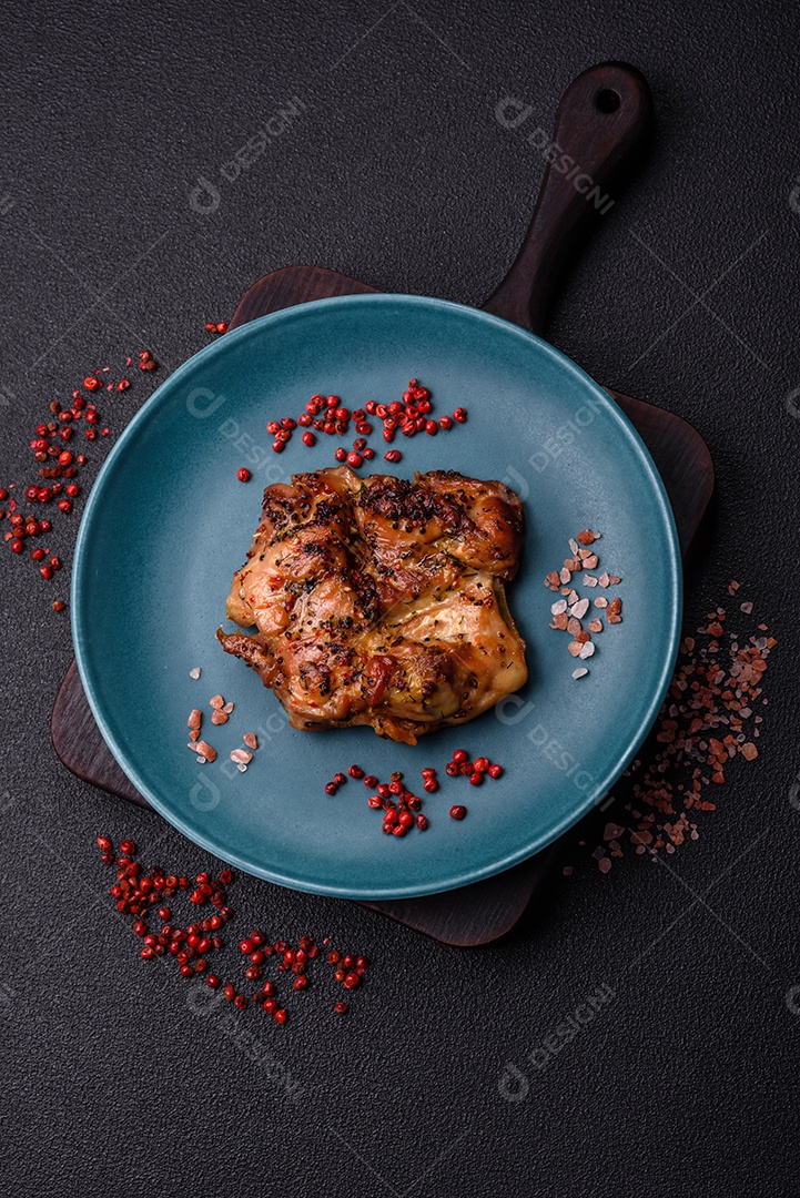 Delicioso bife de frango suculento com sal, especiarias e ervas sobre um fundo escuro de concreto