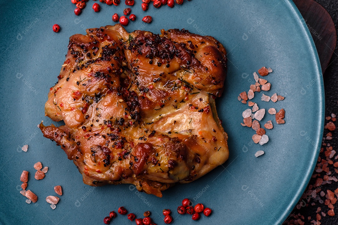 Delicioso bife de frango suculento com sal, especiarias e ervas sobre um fundo escuro de concreto