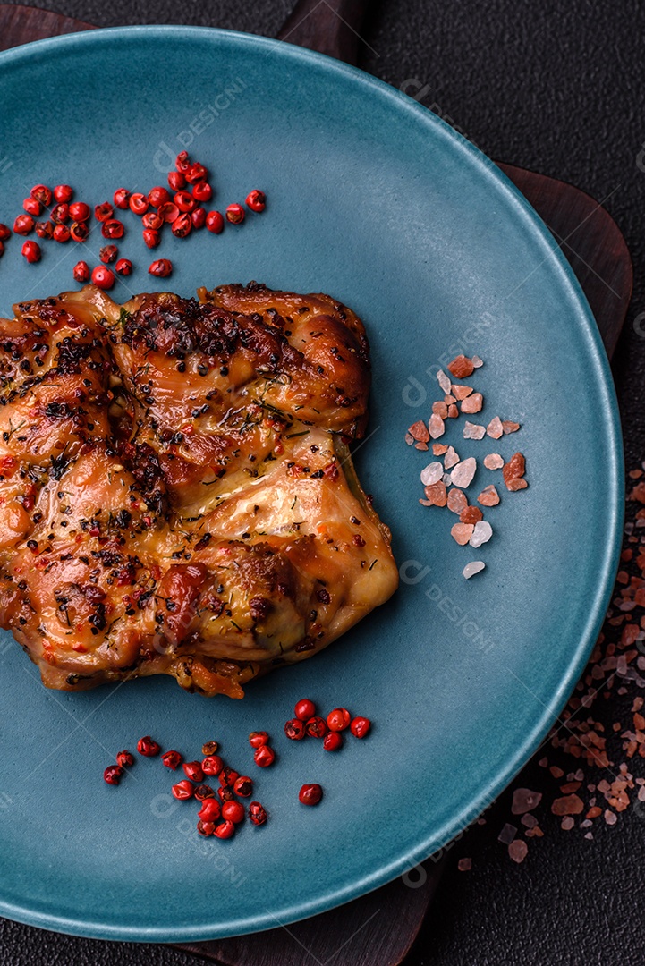 Delicioso bife de frango suculento com sal, especiarias e ervas sobre um fundo escuro de concreto