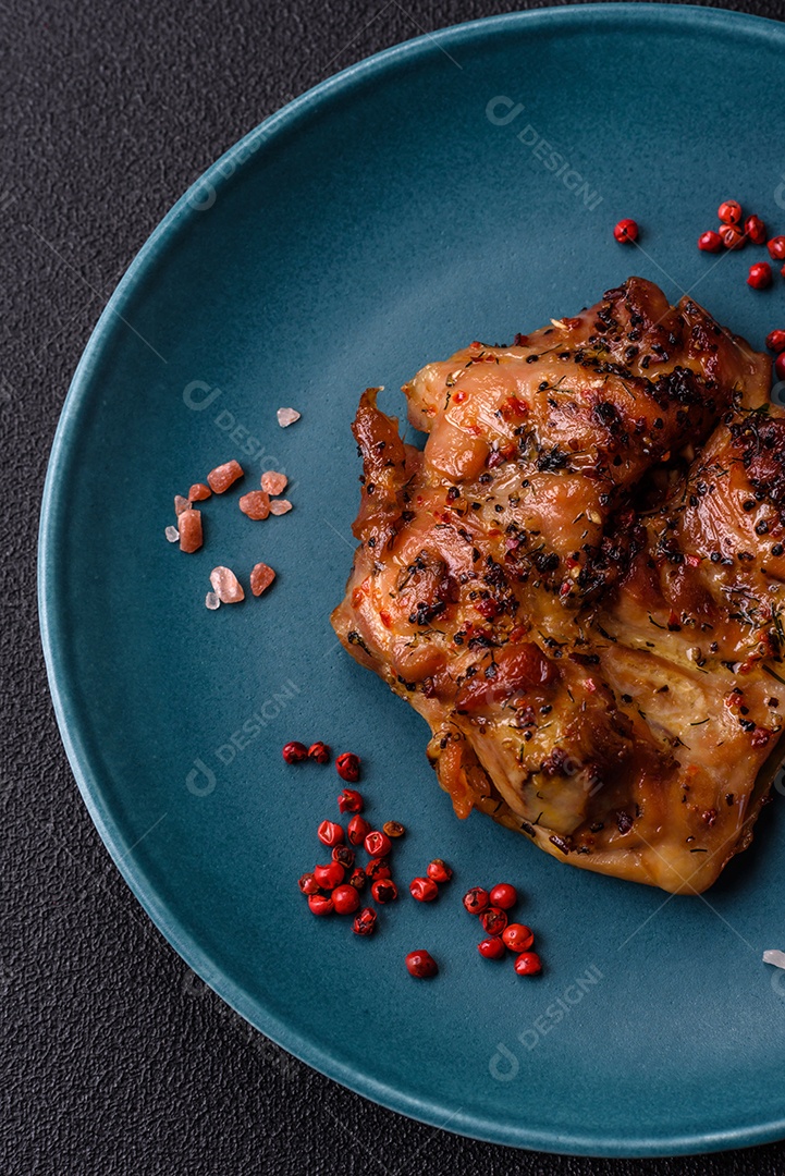 Delicioso bife de frango suculento com sal, especiarias e ervas sobre um fundo escuro de concreto