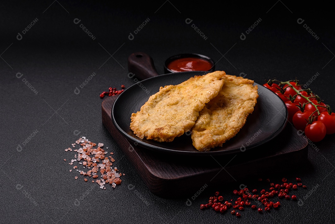 Deliciosas costeletas de frango suculentas em massa com sal, especiarias e ervas sobre um fundo escuro de concreto