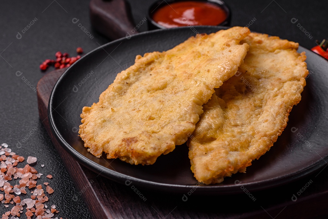 Deliciosas costeletas de frango suculentas em massa com sal, especiarias e ervas sobre um fundo escuro de concreto