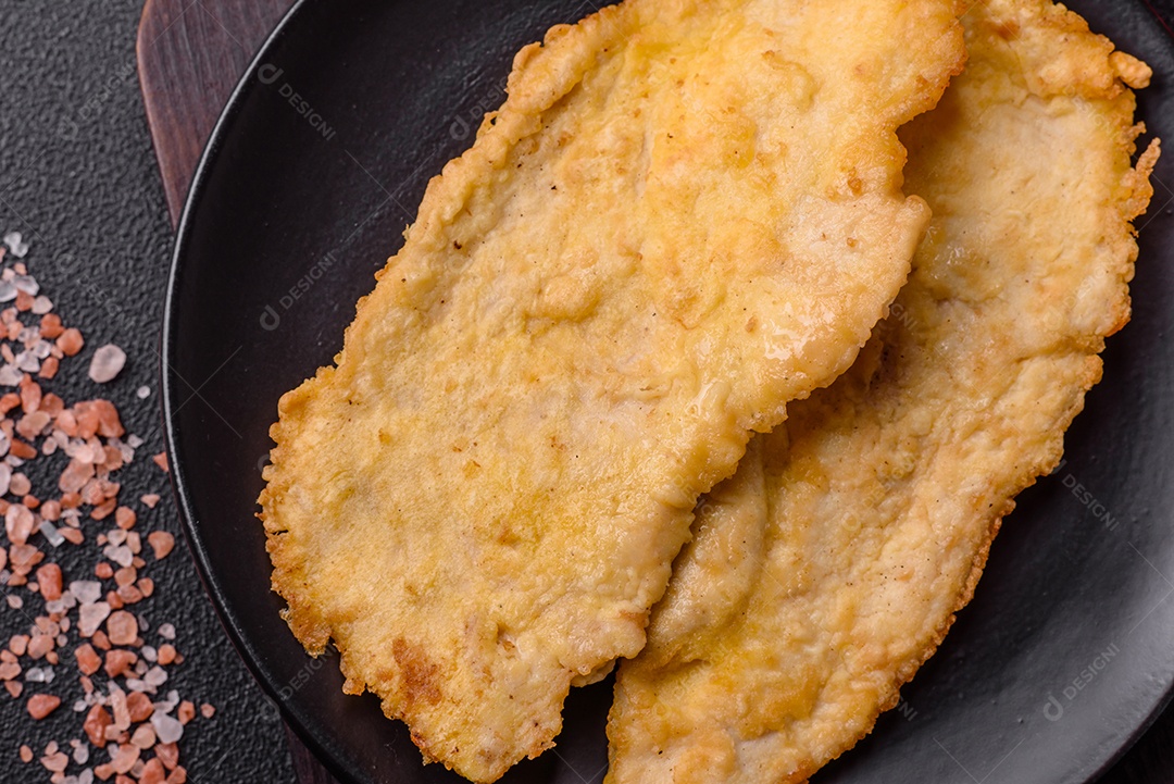 Deliciosas costeletas de frango suculentas em massa com sal, especiarias e ervas sobre um fundo escuro de concreto