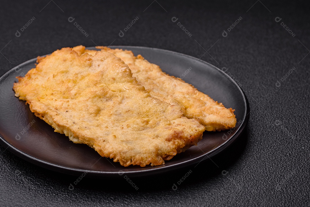 Deliciosas costeletas de frango suculentas em massa com sal, especiarias e ervas sobre um fundo escuro de concreto