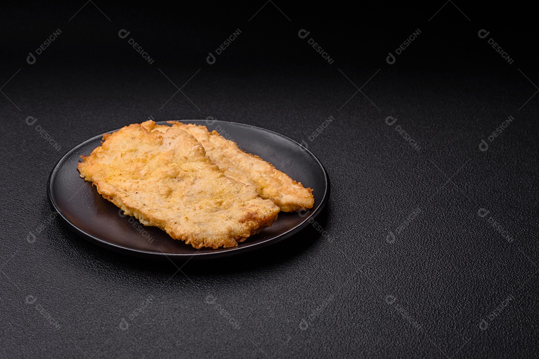 Deliciosas costeletas de frango suculentas em massa com sal, especiarias e ervas sobre um fundo escuro de concreto