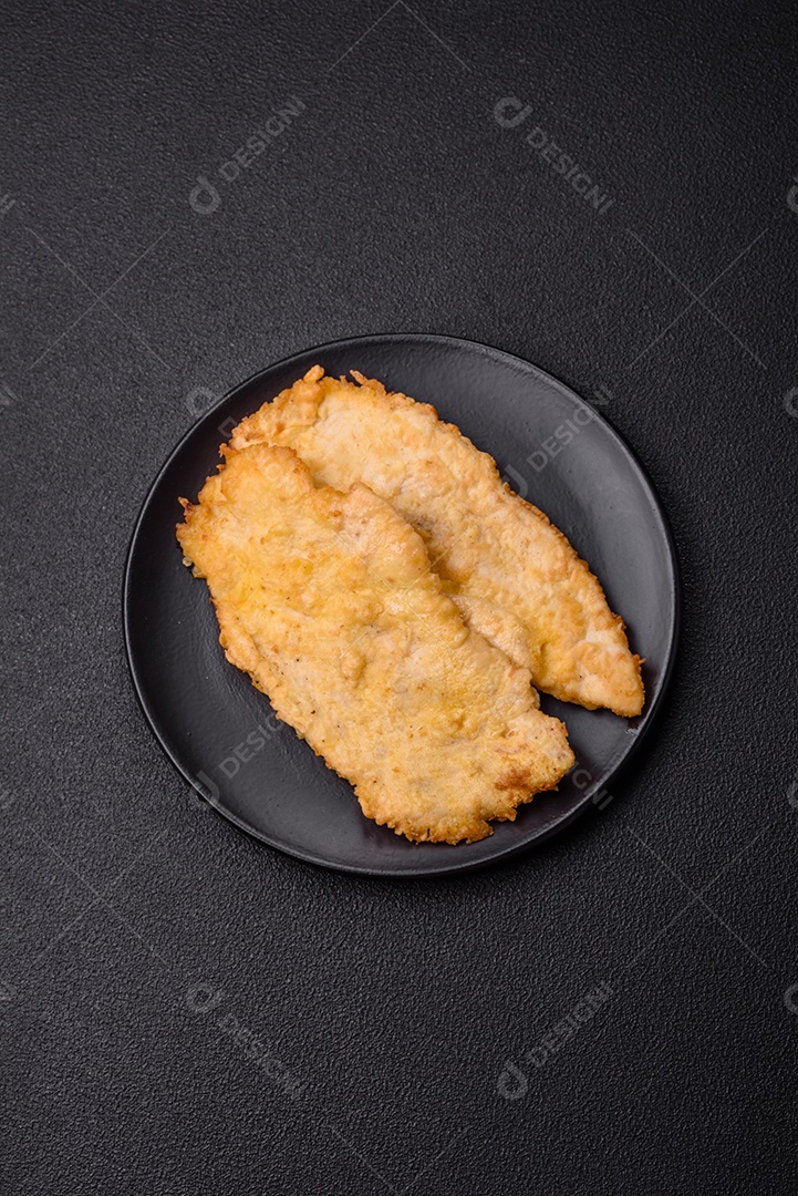 Deliciosas costeletas de frango suculentas em massa com sal, especiarias e ervas sobre um fundo escuro de concreto