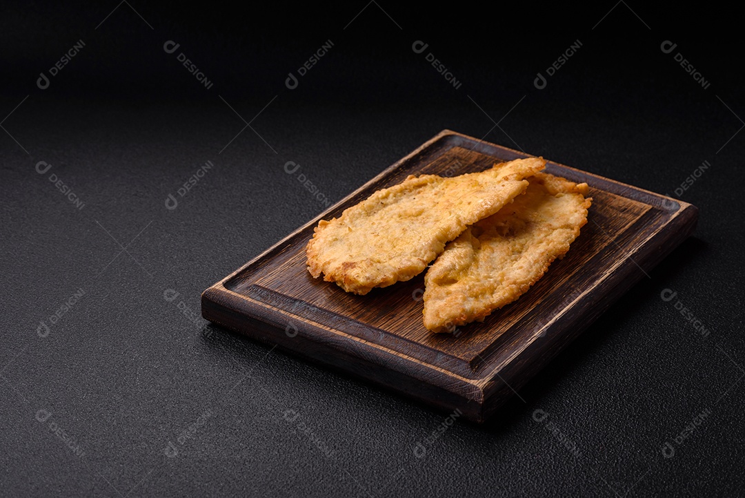 Deliciosas costeletas de frango suculentas em massa com sal, especiarias e ervas sobre um fundo escuro de concreto