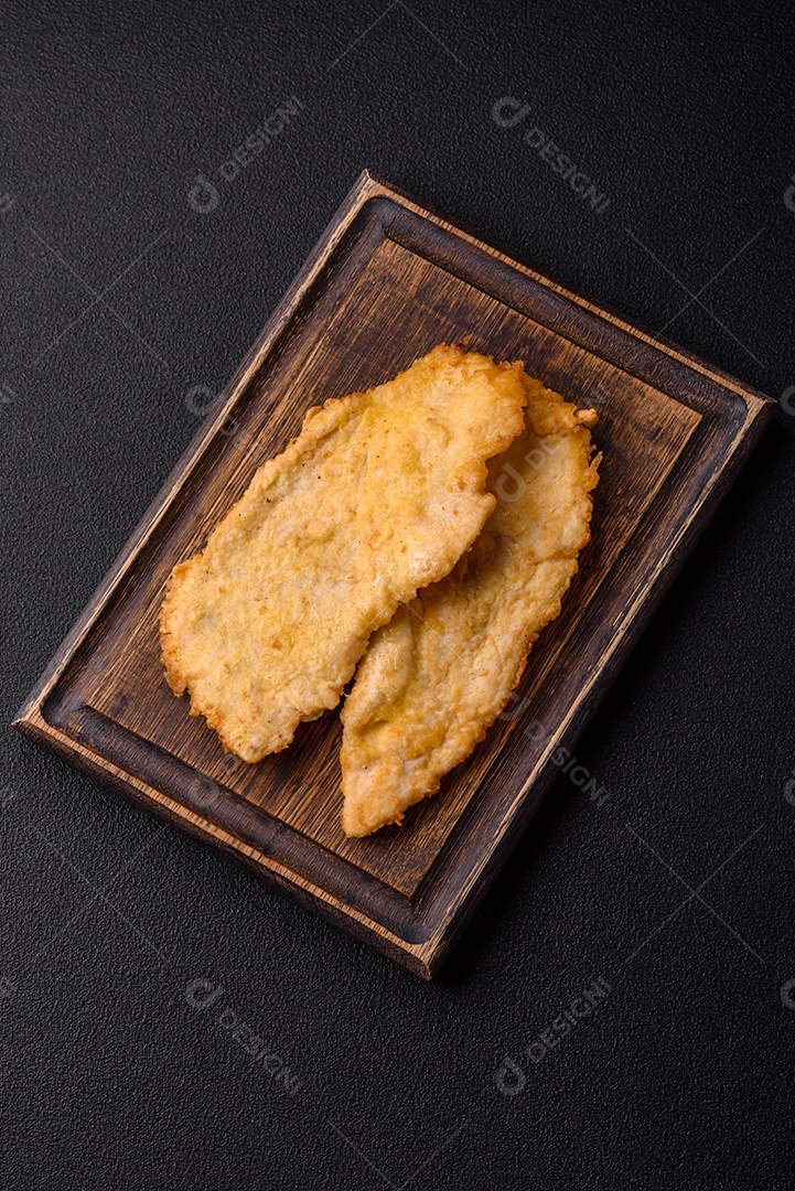 Deliciosas costeletas de frango suculentas em massa com sal, especiarias e ervas sobre um fundo escuro de concreto