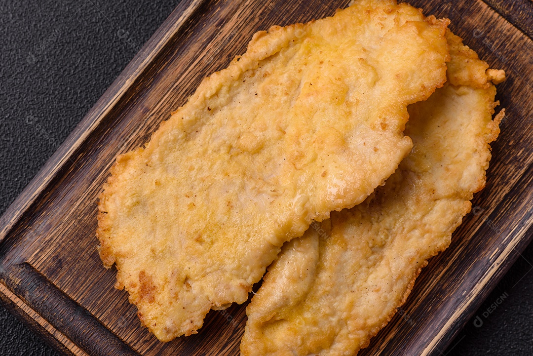 Deliciosas costeletas de frango suculentas em massa com sal, especiarias e ervas sobre um fundo escuro de concreto