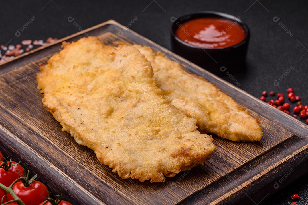 Deliciosas costeletas de frango suculentas em massa com sal, especiarias e ervas sobre um fundo escuro de concreto