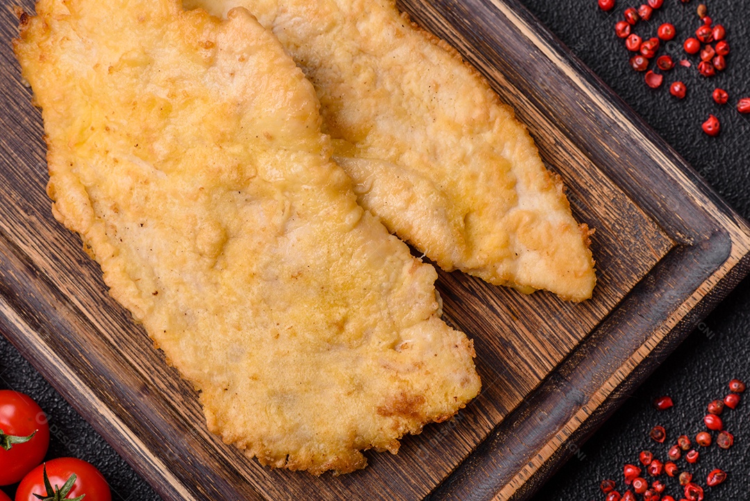 Deliciosas costeletas de frango suculentas em massa com sal, especiarias e ervas sobre um fundo escuro de concreto