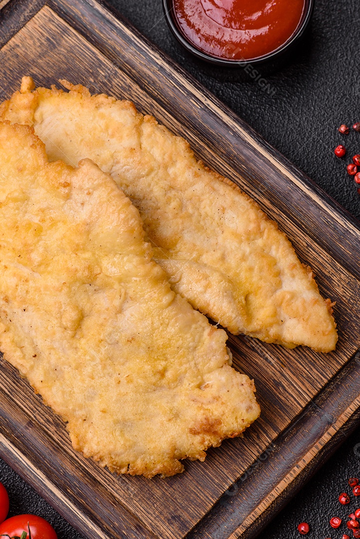 Deliciosas costeletas de frango suculentas em massa com sal, especiarias e ervas sobre um fundo escuro de concreto