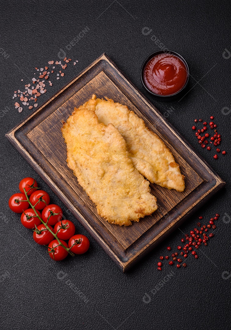 Deliciosas costeletas de frango suculentas em massa com sal, especiarias e ervas sobre um fundo escuro de concreto