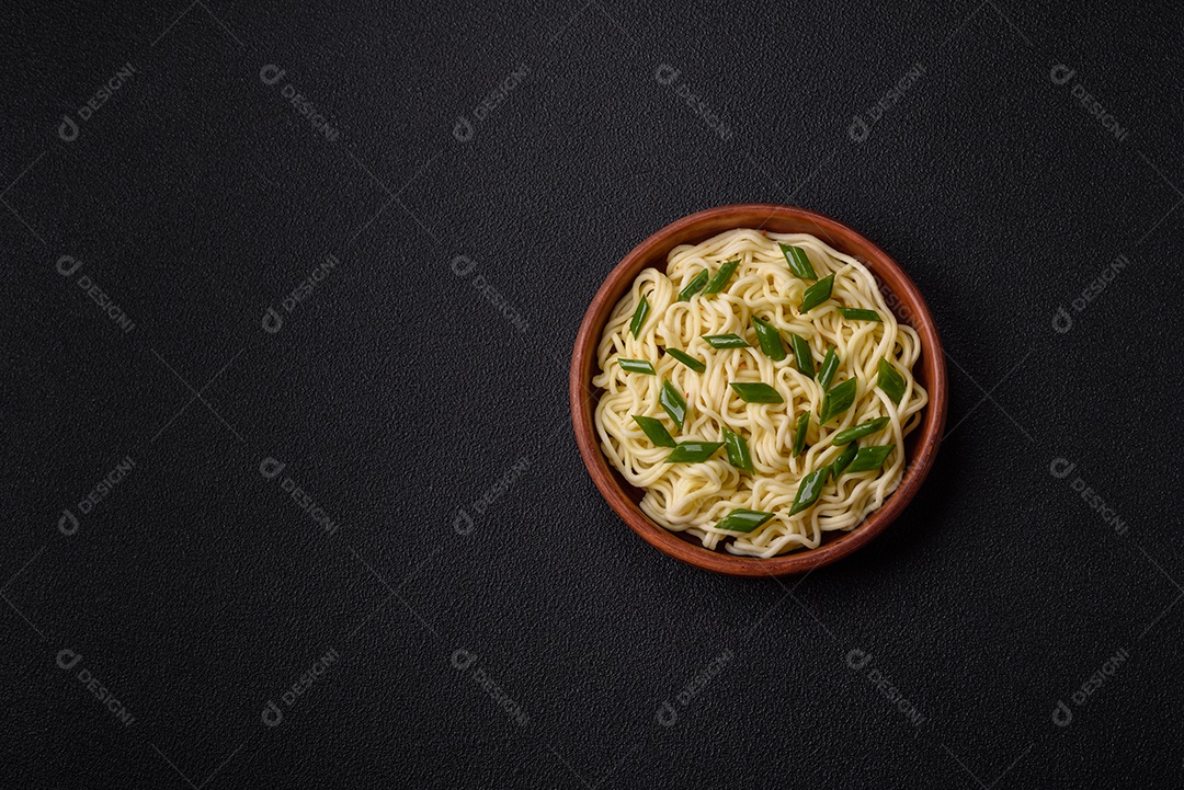 Delicioso prato de cozinha asiática com macarrão de arroz, pimentão, cogumelos e especiarias sobre fundo escuro de concreto