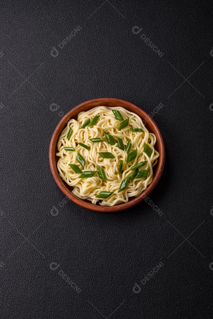 Delicioso prato de cozinha asiática com macarrão de arroz, pimentão, cogumelos e especiarias sobre fundo escuro de concreto