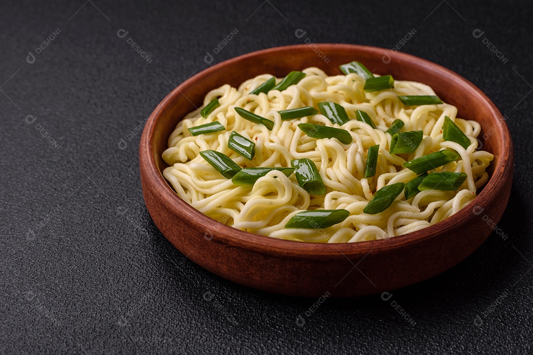 Delicioso prato de cozinha asiática com macarrão de arroz, pimentão, cogumelos e especiarias sobre fundo escuro de concreto