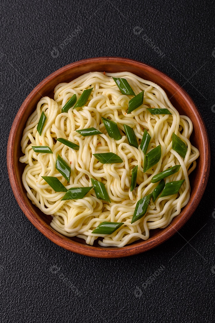 Delicioso prato de cozinha asiática com macarrão de arroz, pimentão, cogumelos e especiarias sobre fundo escuro de concreto