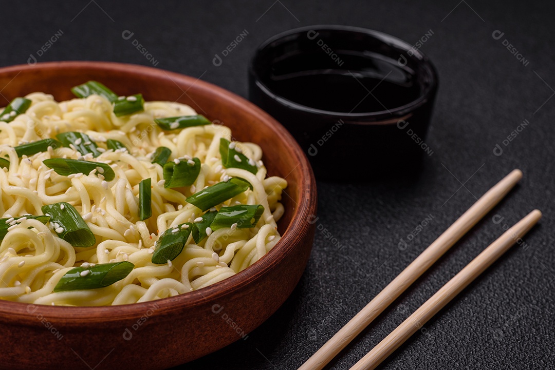 Delicioso prato de cozinha asiática com macarrão de arroz, pimentão, cogumelos e especiarias sobre fundo escuro de concreto