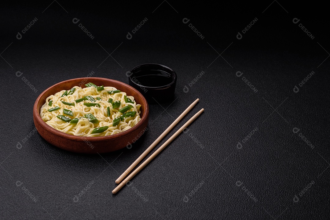 Delicioso prato de cozinha asiática com macarrão de arroz, pimentão, cogumelos e especiarias sobre fundo escuro de concreto