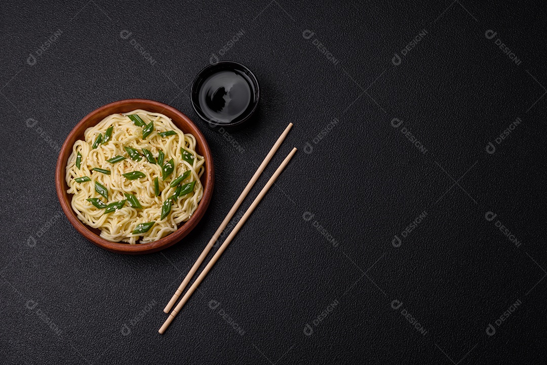 Delicioso prato de cozinha asiática com macarrão de arroz, pimentão, cogumelos e especiarias sobre fundo escuro de concreto