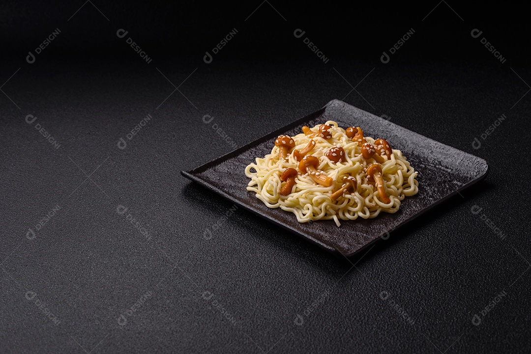 Delicioso prato de cozinha asiática com macarrão de arroz, pimentão, cogumelos e especiarias sobre fundo escuro de concreto